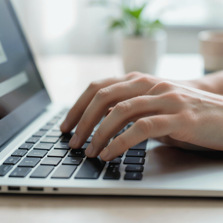 Tangan profesional sedang mengetik di laptop, melambangkan proses penyusunan email lamaran kerja.