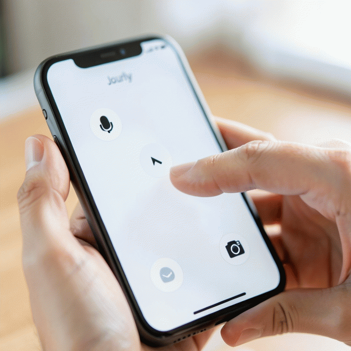 Tangan seseorang yang berinteraksi dengan antarmuka aplikasi jurnal digital yang minimalis, menunjukkan tiga mode input (suara, teks, gambar) yang mudah diakses.